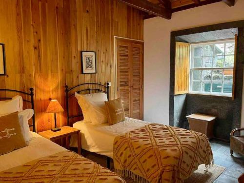 a bedroom with two beds and a window at Casa da Terra Alta in Santo Amaro