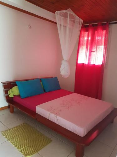a bed in a room with a red window at F1 studio Martinique in Quartier la Fleury Guiné