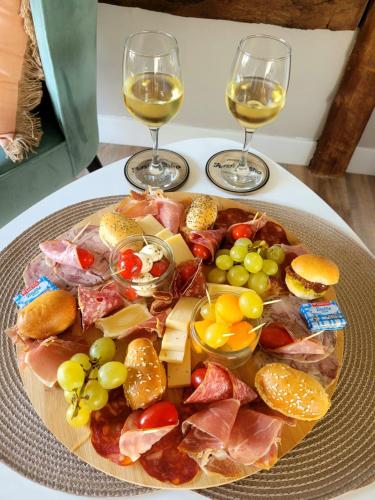 a plate of food on a table with two glasses of wine at Les Gites de l'Herperie in Blicourt