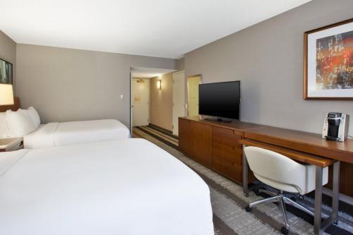 a hotel room with a bed and a desk with a television at Crowne Plaza Dulles Airport by IHG in Herndon