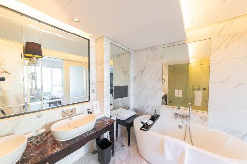 a bathroom with two sinks and a tub and a large mirror at Marco Polo Xiamen in Xiamen