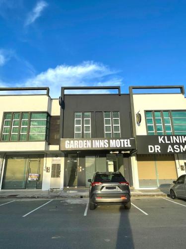 a car parked in a parking lot in front of a building at Garden Inns Motel in Kangar