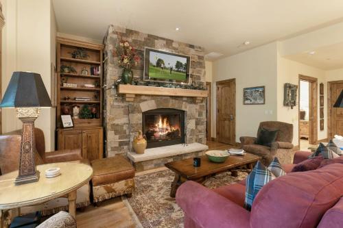 sala de estar con chimenea de piedra y TV en B107 Beaver Creek Landing condo en Beaver Creek