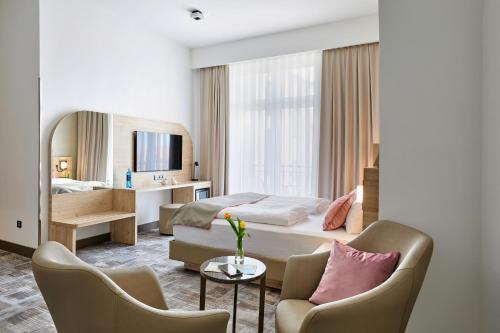 a hotel room with a bed and two chairs at Hotel KAISERHOF in Bitterfeld