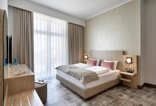 - une chambre avec un grand lit et une grande fenêtre dans l'établissement Hotel KAISERHOF, à Bitterfeld
