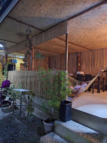 a person laying in a hammock in a covered porch at Rain Haven Lodging House in Coron