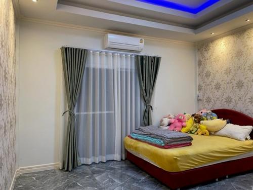 una camera da letto con un letto con lenzuola gialle e animali di peluche di บ้านนายหัว ก ชุมพร a Ban Tha Samet (1)
