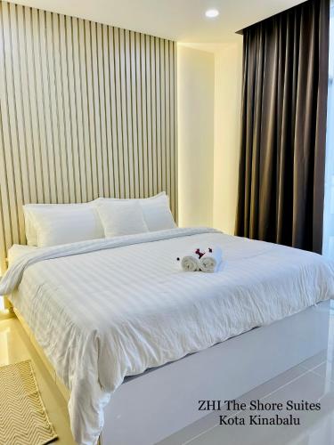 a bed with two stuffed animals on top of it at ZHI The Shore Suites Kota Kinabalu in Kota Kinabalu