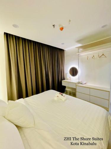 a bedroom with a large white bed and a mirror at ZHI The Shore Suites Kota Kinabalu in Kota Kinabalu