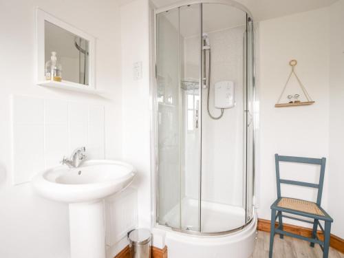 a white bathroom with a sink and a shower at Heron Cottage in Colyton