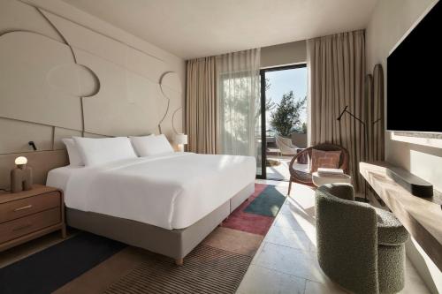 a bedroom with a large white bed and a tv at W Costa Navarino in Pylos