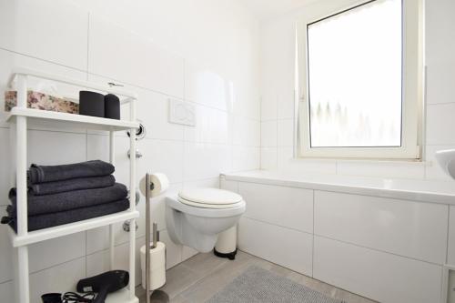 La salle de bains blanche est pourvue de toilettes, d'une baignoire et d'une fenêtre. dans l'établissement Air Apartments 5, à Brême