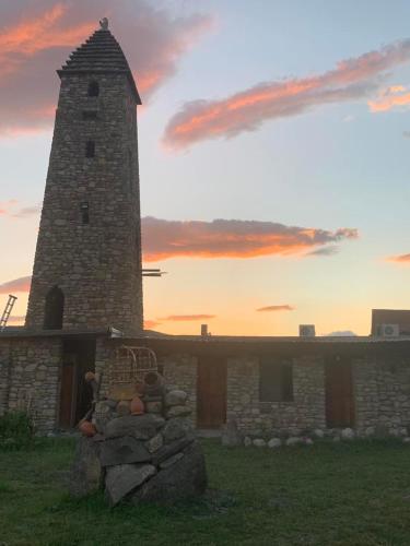 a stone building with a tower and a pile of rocks at Golden Cradle in Bazalet'i