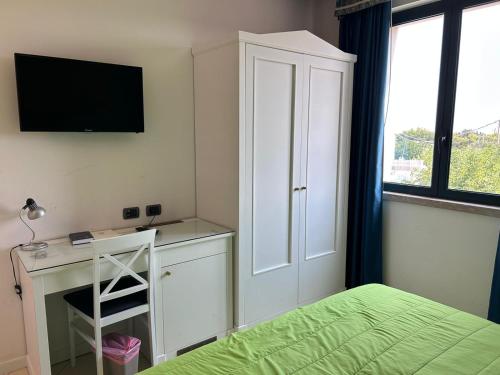 een slaapkamer met een bed en een bureau met een televisie bij Tuo Hotel in Polignano a Mare