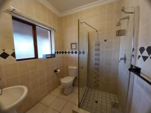 a bathroom with a shower and a toilet and a sink at The Diamond in Pretoria