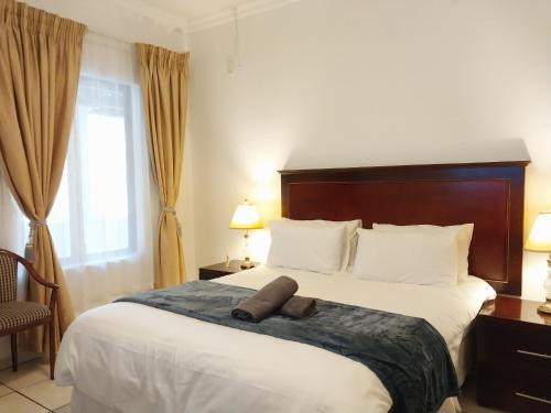 Habitación de hotel con cama grande y cabecero marrón en The Diamond, en Pretoria
