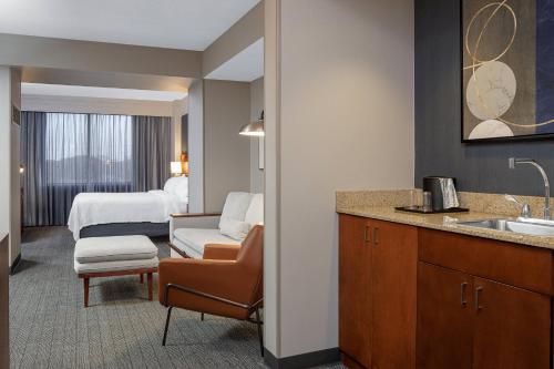 a hotel room with a sink and a bedroom at Courtyard Long Island MacArthur Airport in Ronkonkoma