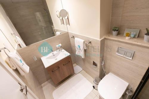 uma casa de banho com um WC branco e um lavatório. em Lavish Pool View Apartment em Abu Dhabi