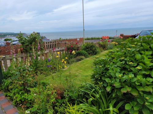 un jardín con flores y el océano en el fondo en Seaside Flat with Fast WiFi, en Scarborough