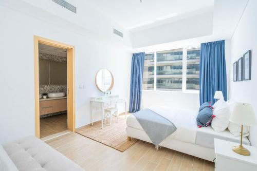 a white bedroom with a bed and a mirror at Modern 2 Br Maid's Room With Amazing View in Abu Dhabi