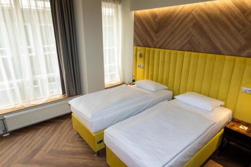 duas camas num quarto com amarelo e branco em City Hotel Pilvax em Budapeste