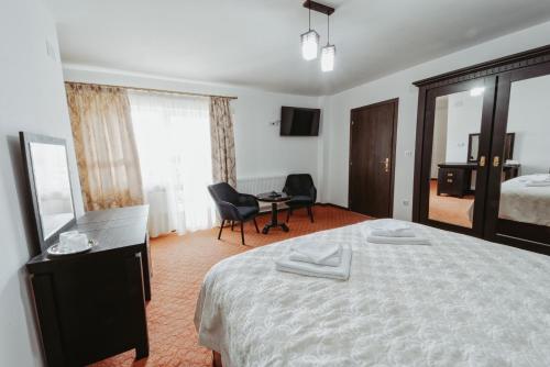 a hotel room with a bed and a table and chairs at Complex Turistic Constantin Bucovina in Câmpulung Moldovenesc