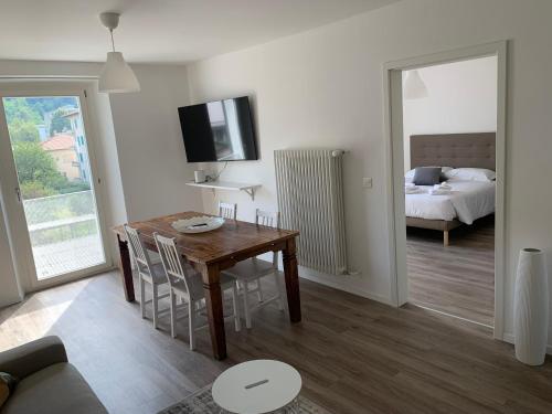 a living room with a wooden table and a bedroom at Smart Living Swiss in Chiasso