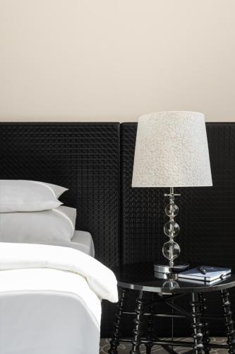 a table with a lamp on it next to a bed at Falkensteiner Hotel Belgrade Superior in Belgrade
