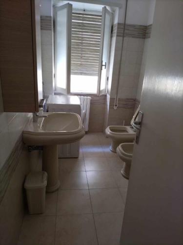 uma casa de banho com 2 WC, um lavatório e uma janela em Casa Maria em Terracina