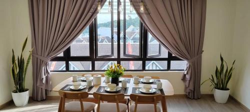 a dining room with a table and chairs and a large window at Utopia Homestay @ Cameron Centrum in Cameron Highlands