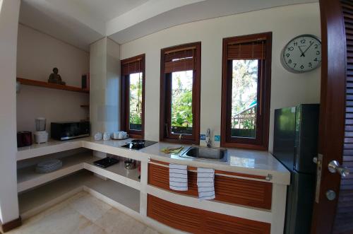 a kitchen with a sink and a clock on the wall at Villa Rumah Isah in Candidasa