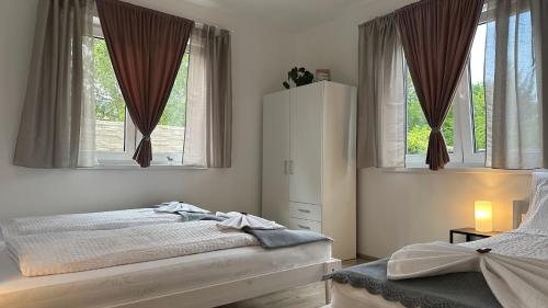 a bedroom with a bed and two windows at Relax House Mohelnice in Mohelnice