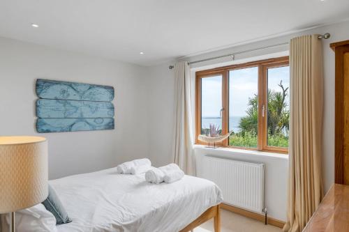 a white bedroom with a bed and a window at Rosemerryn in Marazion
