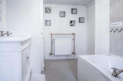 a white bathroom with a sink and a bath tub at Angel Cottage - 3 Bedroom Cottage - Stepaside in Stepaside