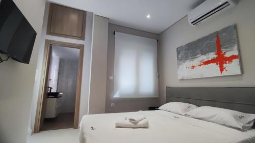a bedroom with a bed with white sheets and a tv at Luxury Apartment Stella in Piraeus