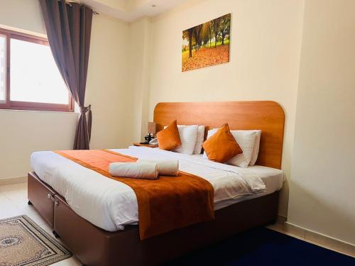 a bedroom with a large bed with orange pillows at Marhaba Deira Hotel in Dubai