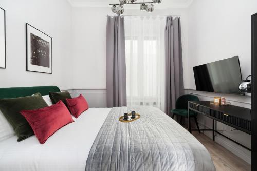 Schlafzimmer mit einem Bett mit roten Kissen und einem TV in der Unterkunft Cracovian House by LoftAffair in Krakau
