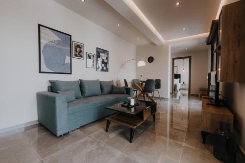 een woonkamer met een blauwe bank en een tafel bij Pearl Apartel in Volos