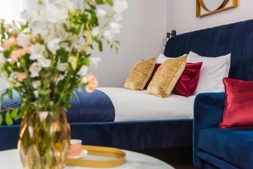 a living room with a blue couch and a vase of flowers at Cracovian House - LoftAffair in Kraków