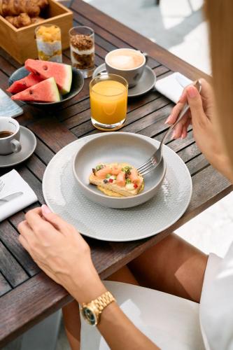 a person sitting at a table with a plate of food at Falkensteiner Hotel Belgrade Superior in Belgrade
