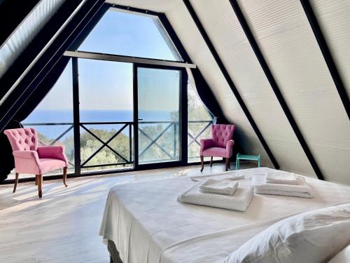 a bedroom with a bed and two chairs and a large window at villa calippo in Antalya