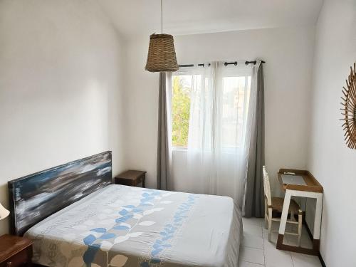 Schlafzimmer mit einem Bett und einem Fenster in der Unterkunft BEACH APARTMENT PEREYBERE in Pereybere