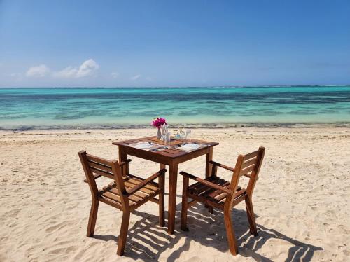 a table and two chairs on the beach at Almas Beach Boutique Hotel in Makunduchi