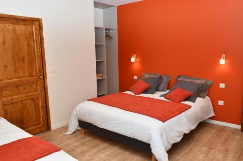 une chambre avec deux lits et un mur orange dans l'établissement Grande maison de vacances Les Reinettes, à Cheffois