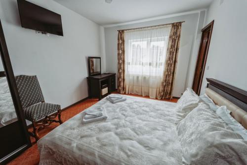 a bedroom with a large white bed and a chair at Complex Turistic Constantin Bucovina in Câmpulung Moldovenesc