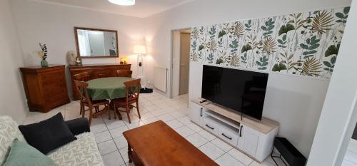 a living room with a flat screen tv and a table at T2 55m² tout confort avec jardin. Cuisine et équipements neufs. Wifi TV parking in Balma