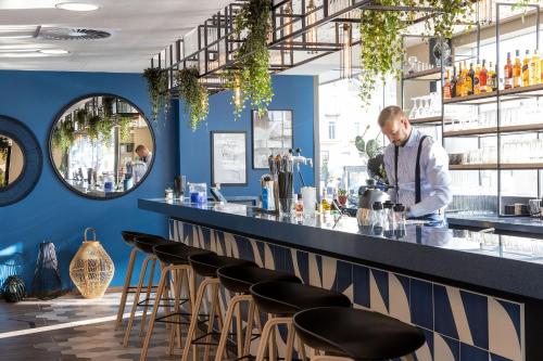 un homme debout à un comptoir dans un bar dans l'établissement Hampton by Hilton Tours Centre, France, à Tours