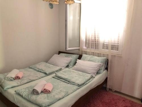 a bed with two slippers on it with a window at Kuca za odmor DIVA in Mostar