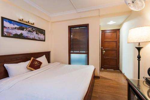a bedroom with a bed and a lamp and a door at May Ho Hotel Sapa in Sa Pa