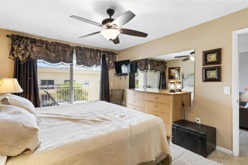 a bedroom with a bed with a ceiling fan and a window at 208 Madeira Norte Condo in St Pete Beach